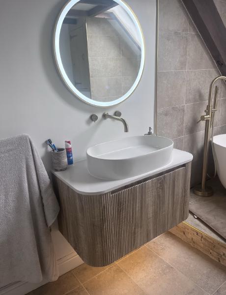 Illuminated LED bathroom mirror above a wall-hung vanity unit, wired in Stafford