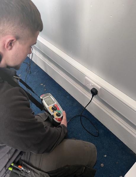 Electrician testing a socket outlet with a multifunction tester during an EICR