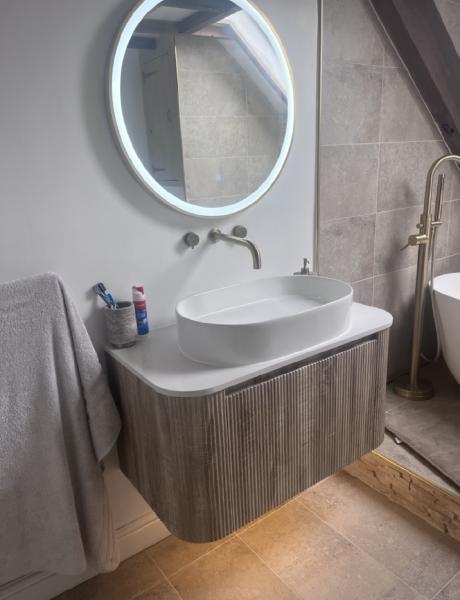 LED illuminated round mirror and wall lighting in a tiled ensuite bathroom